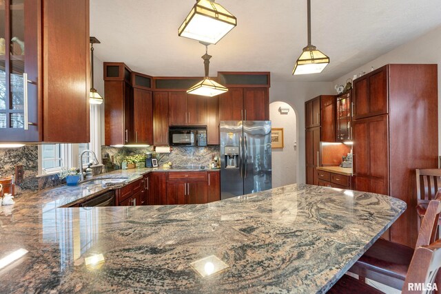 kitchen featuring a kitchen bar, kitchen peninsula, sink, decorative light fixtures, and stainless steel fridge with ice dispenser