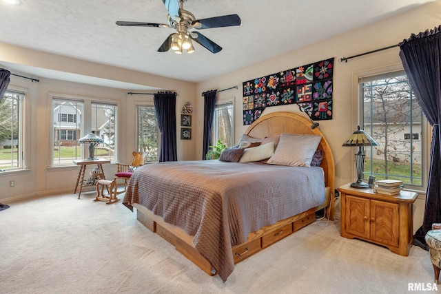 bedroom featuring a textured ceiling, light colored carpet, and ceiling fan