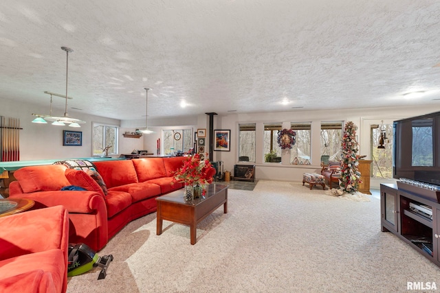 carpeted living room with a wood stove and a textured ceiling