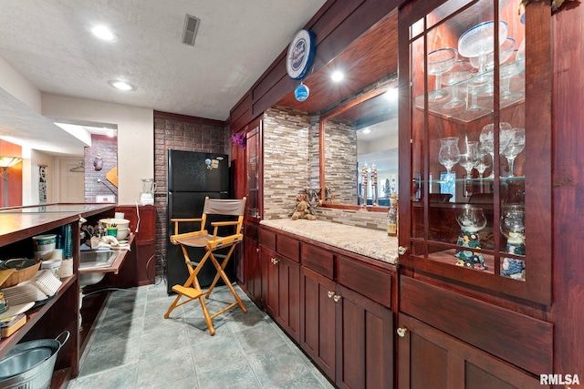 bar with decorative backsplash, light stone countertops, and a textured ceiling