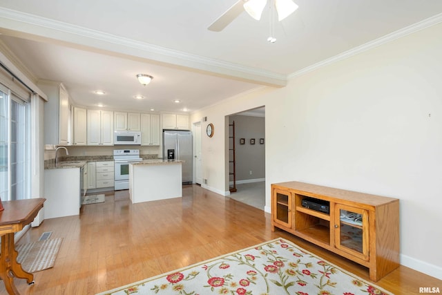 kitchen featuring light wood-type flooring, ornamental molding, white appliances, a center island, and white cabinetry