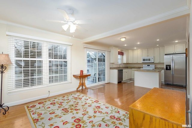 kitchen with white cabinets, appliances with stainless steel finishes, a center island, and light wood-type flooring