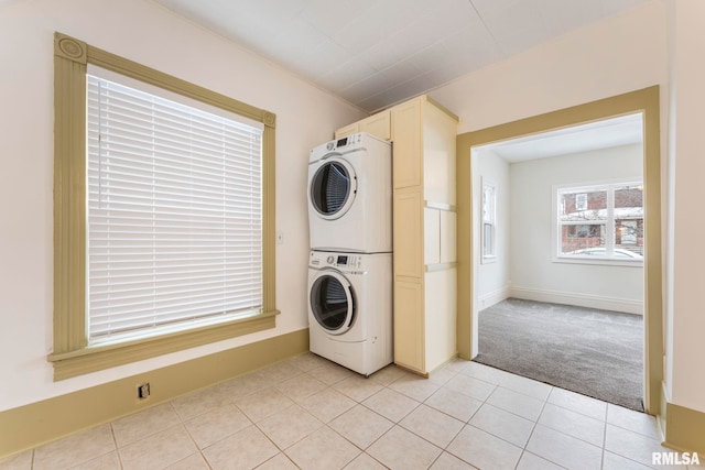 washroom with stacked washer / dryer and light tile patterned floors