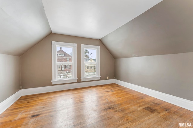 additional living space featuring light wood-type flooring and vaulted ceiling