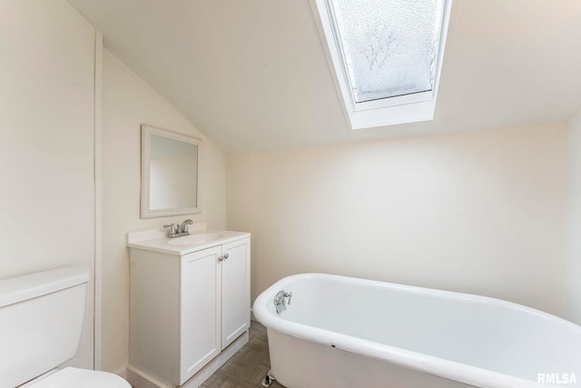 bathroom with a bathing tub, lofted ceiling with skylight, vanity, and toilet