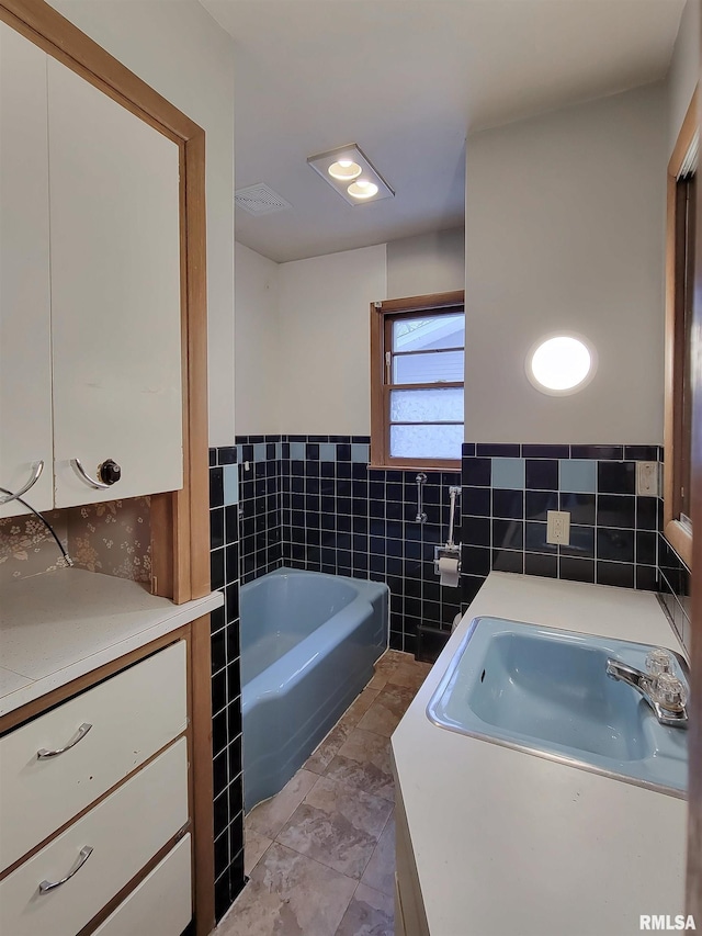 bathroom featuring vanity, a tub to relax in, and tile walls