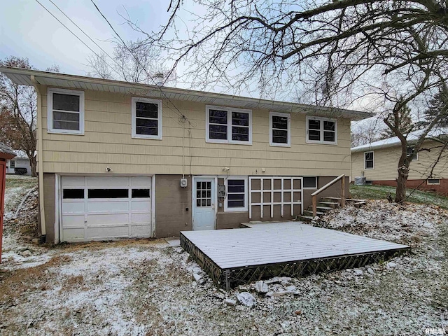 snow covered back of property featuring a garage and a wooden deck