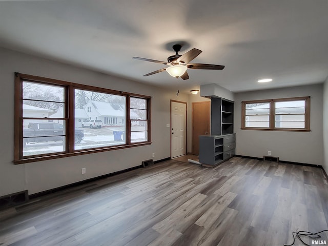 unfurnished living room featuring a wealth of natural light, ceiling fan, and hardwood / wood-style flooring