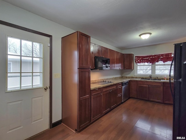 kitchen with sink, dark hardwood / wood-style floors, light stone counters, and black appliances