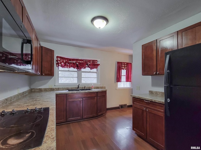 kitchen with sink, a textured ceiling, dark hardwood / wood-style flooring, and black appliances