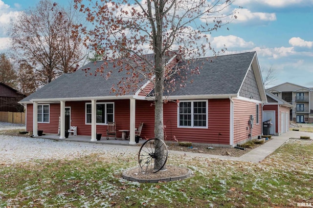 back of property featuring a lawn, a garage, and covered porch