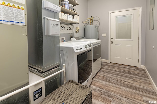 laundry room with heating unit, water heater, wood-type flooring, washing machine and clothes dryer, and electric panel