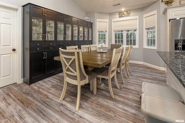 dining space featuring light hardwood / wood-style floors and vaulted ceiling