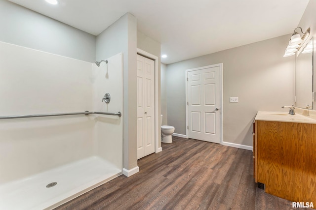 bathroom featuring wood-type flooring, toilet, vanity, and walk in shower