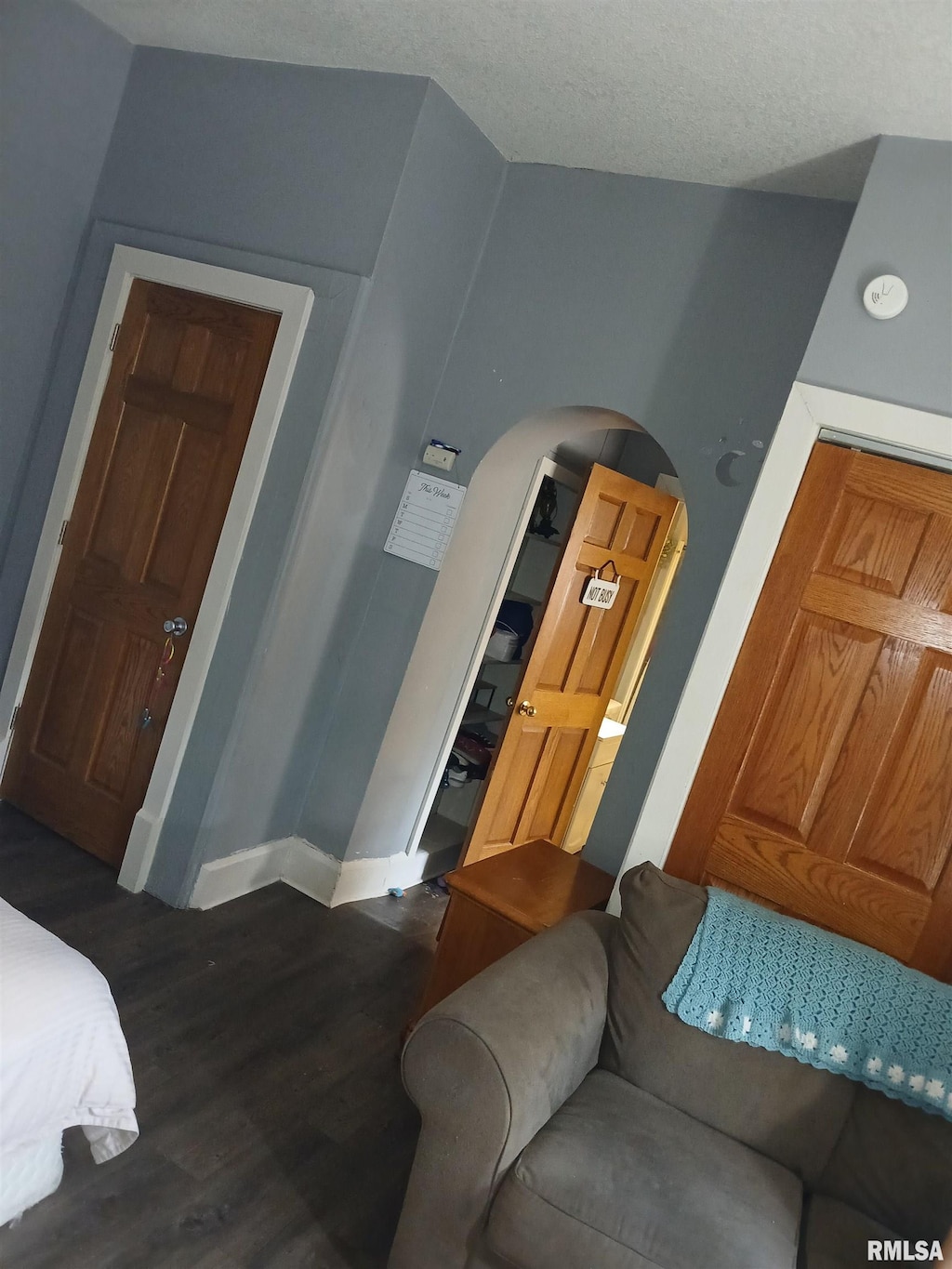 bedroom with a textured ceiling, dark hardwood / wood-style floors, and lofted ceiling