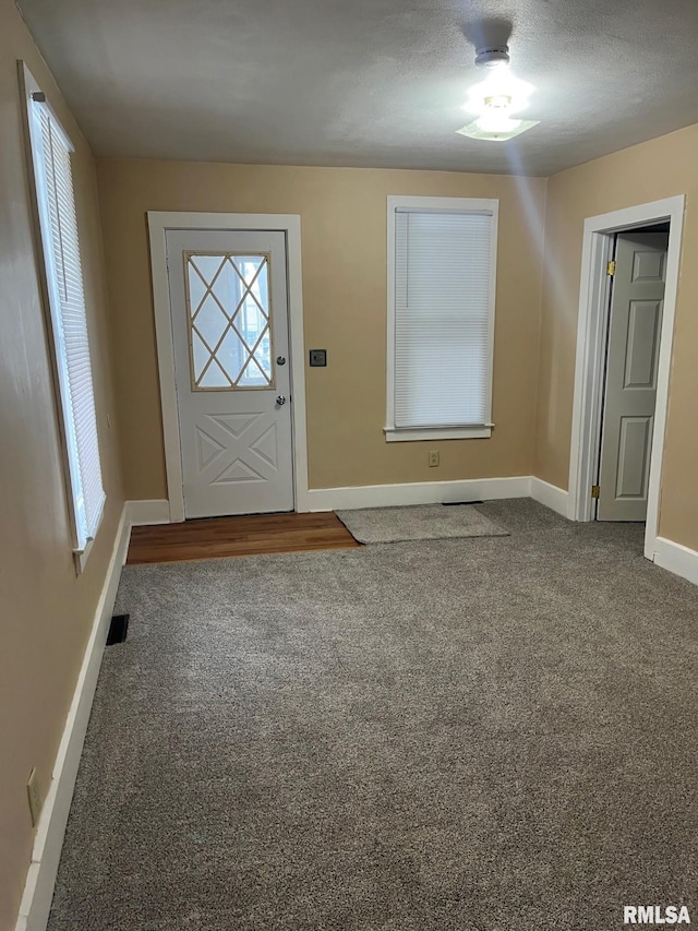 carpeted foyer with a textured ceiling