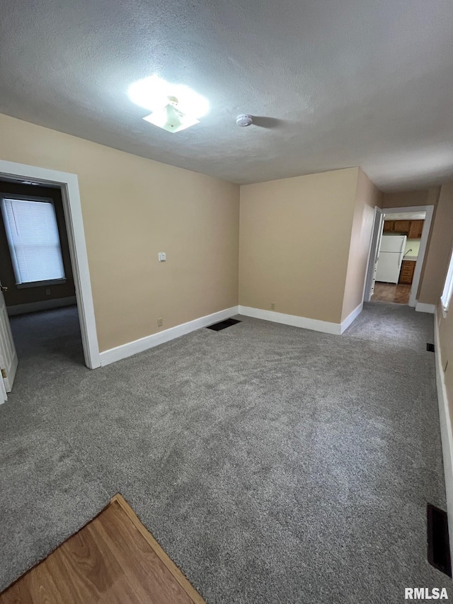 empty room with dark colored carpet and a textured ceiling