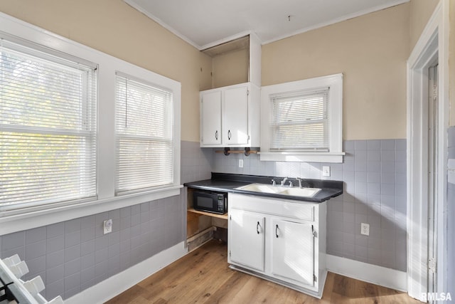 kitchen with crown molding, sink, white cabinets, and light wood-type flooring