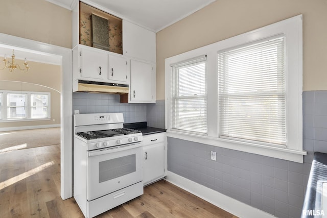 kitchen with an inviting chandelier, white cabinets, light wood-type flooring, and white gas range oven