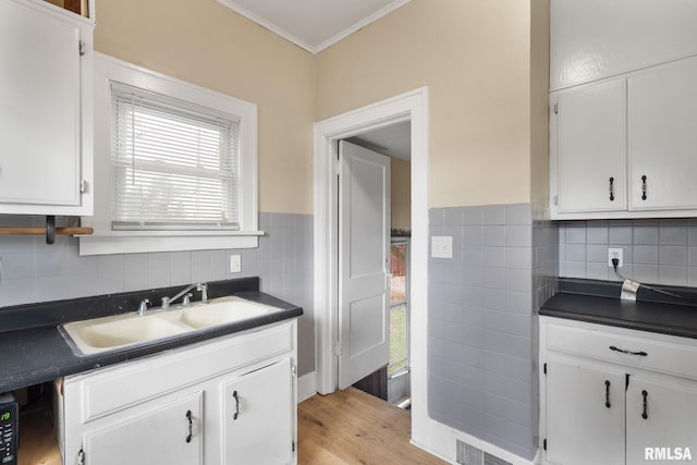 kitchen featuring white cabinets, light hardwood / wood-style flooring, crown molding, and sink