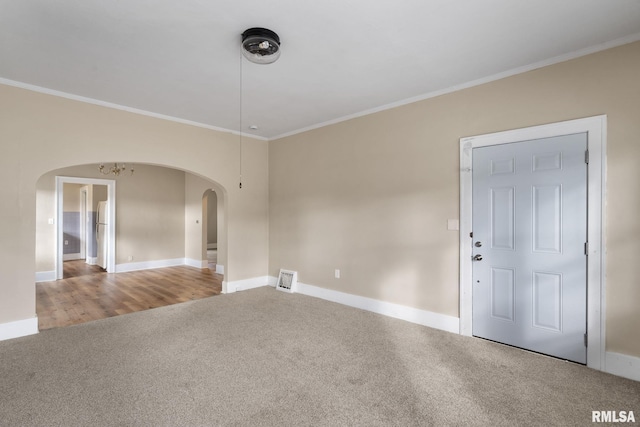 carpeted spare room with a chandelier and ornamental molding