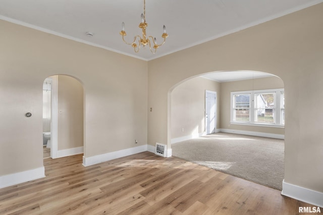 empty room featuring a chandelier, hardwood / wood-style flooring, and crown molding