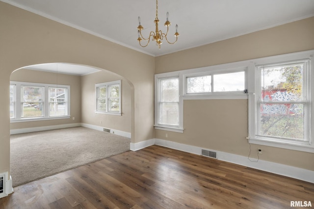 empty room with hardwood / wood-style floors, a notable chandelier, a healthy amount of sunlight, and crown molding