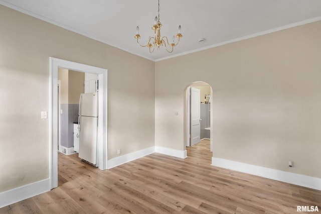 empty room with an inviting chandelier, light hardwood / wood-style floors, and ornamental molding