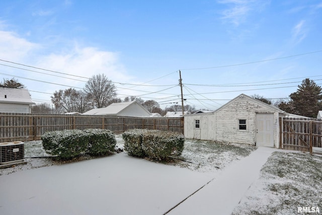 snowy yard featuring an outdoor structure and central AC