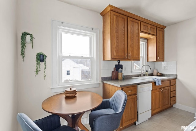 kitchen featuring white dishwasher, sink, a wealth of natural light, and tasteful backsplash