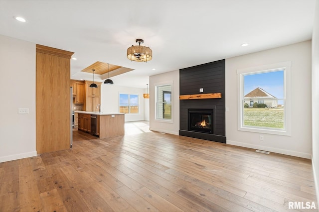 unfurnished living room featuring light wood-type flooring, a large fireplace, and sink