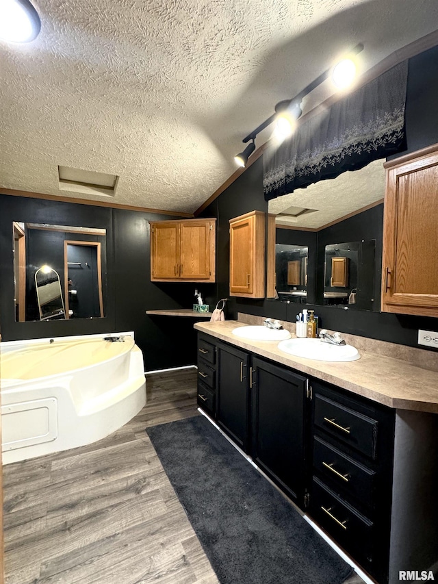 bathroom featuring a bathing tub, hardwood / wood-style floors, lofted ceiling, a textured ceiling, and vanity