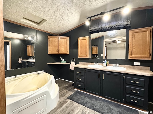 bathroom featuring vanity, vaulted ceiling, ornamental molding, a textured ceiling, and wood-type flooring