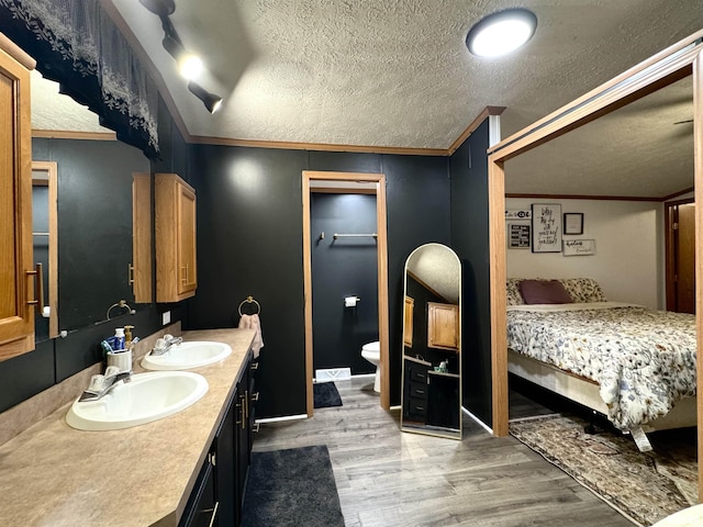 bathroom featuring crown molding, vanity, wood-type flooring, and a textured ceiling