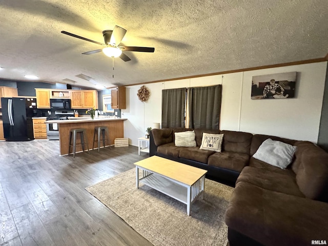 living room with lofted ceiling, dark hardwood / wood-style floors, ceiling fan, ornamental molding, and a textured ceiling