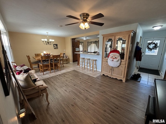 living room with ceiling fan with notable chandelier and light hardwood / wood-style floors