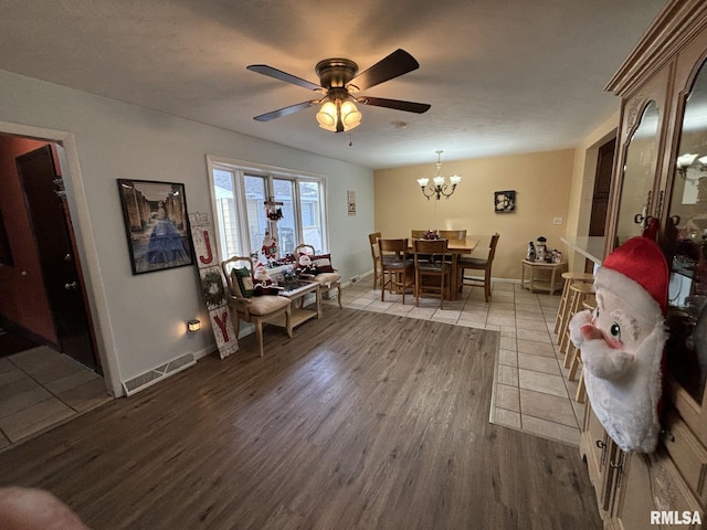 dining room featuring ceiling fan with notable chandelier and wood-type flooring