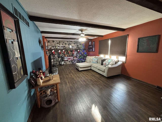 unfurnished living room with ceiling fan, beamed ceiling, dark wood-type flooring, and a textured ceiling