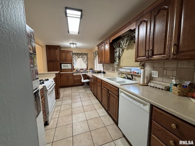 kitchen featuring white appliances, sink, tasteful backsplash, light tile patterned flooring, and kitchen peninsula