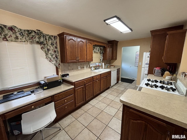 kitchen with dark brown cabinetry, sink, tasteful backsplash, white appliances, and light tile patterned flooring