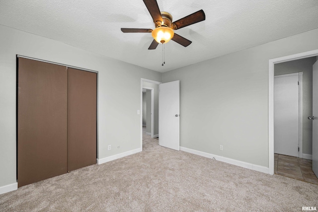 unfurnished bedroom featuring a textured ceiling, ceiling fan, light carpet, and a closet