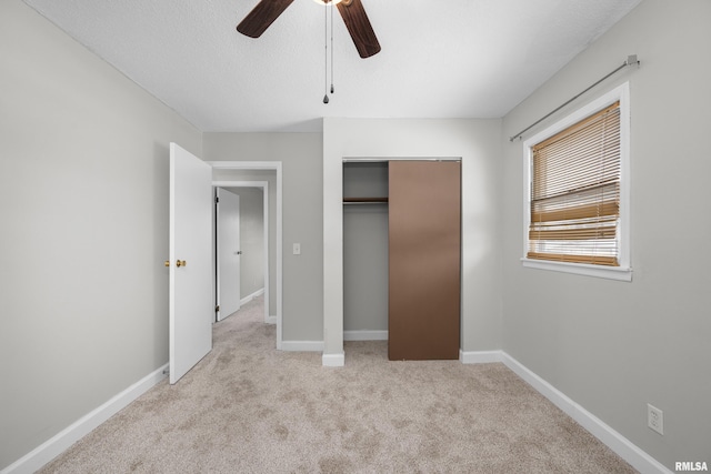 unfurnished bedroom featuring a textured ceiling, ceiling fan, light carpet, and a closet