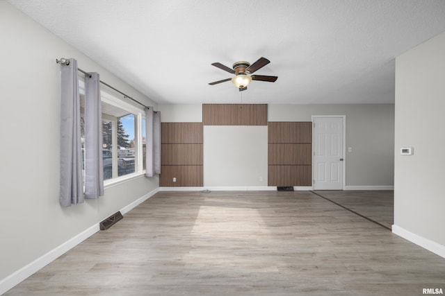 spare room featuring a textured ceiling, light hardwood / wood-style floors, and ceiling fan