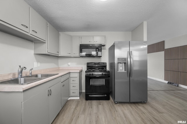 kitchen with sink, light hardwood / wood-style flooring, a textured ceiling, gray cabinets, and black appliances