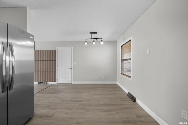 unfurnished dining area featuring wood-type flooring and a textured ceiling