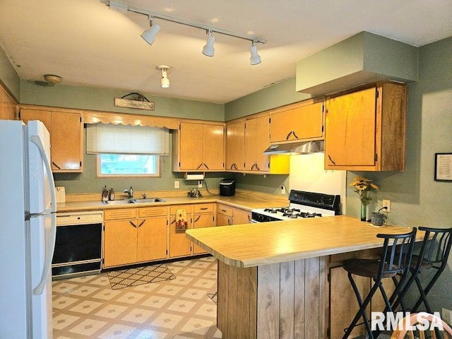 kitchen featuring a breakfast bar, white appliances, track lighting, sink, and kitchen peninsula