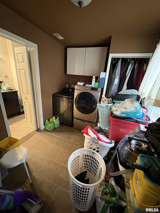 laundry area featuring cabinets, light tile patterned floors, and independent washer and dryer