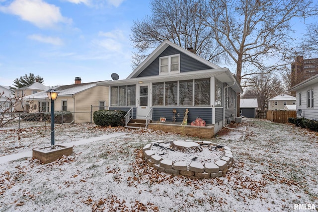 snow covered property featuring a fire pit and a sunroom