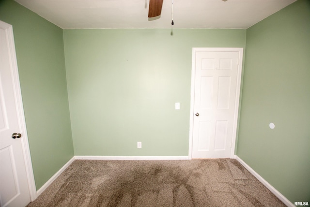 carpeted spare room featuring baseboards and ceiling fan