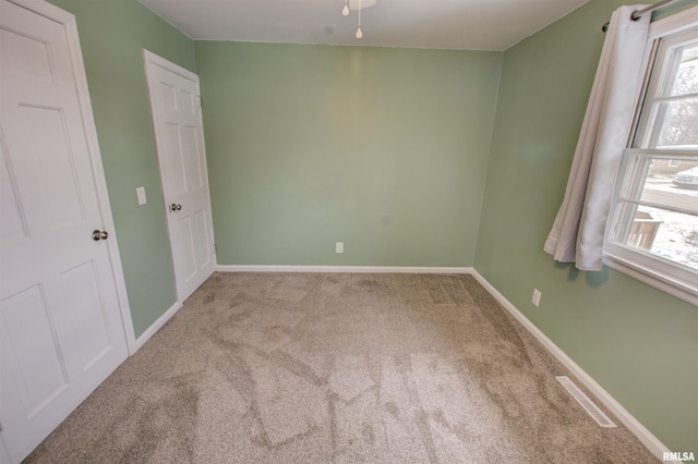 carpeted spare room featuring baseboards and visible vents